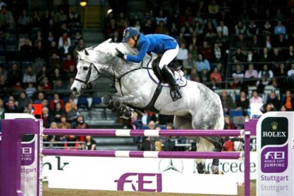 Judy-Ann Melchior riding a gray horse over an oxer.