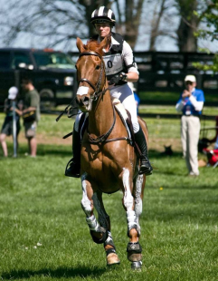 Sinead Halpin galloping on a cross country course riding a chestnut horse