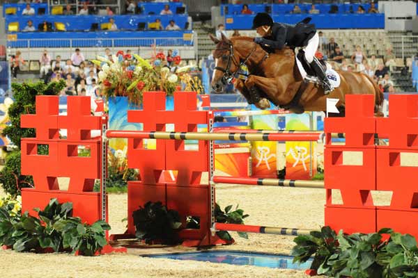 Edwina Tops-Alexander riding a chestnut horse over an oxer.