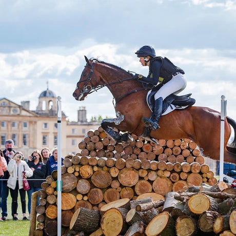 Woodge Fulton on a bay horse jumping a large woodpile