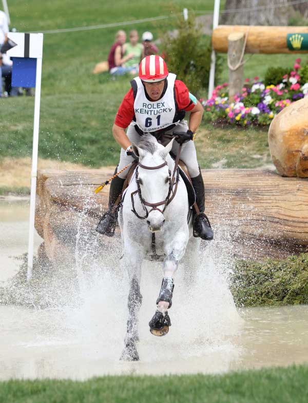 Buck Davidson riding a gray horse through the water complex at the Rolex Kentucky Three-Day Event.