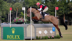 Buck Davidson riding a bay horse over a corner obstacle