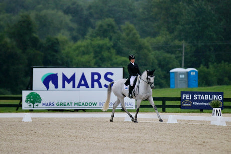 Sharon White riding a gray horse in dressage 